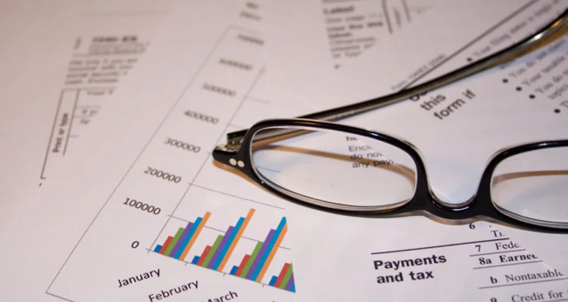 A pair of glasses rests on top of a stack of financial papers